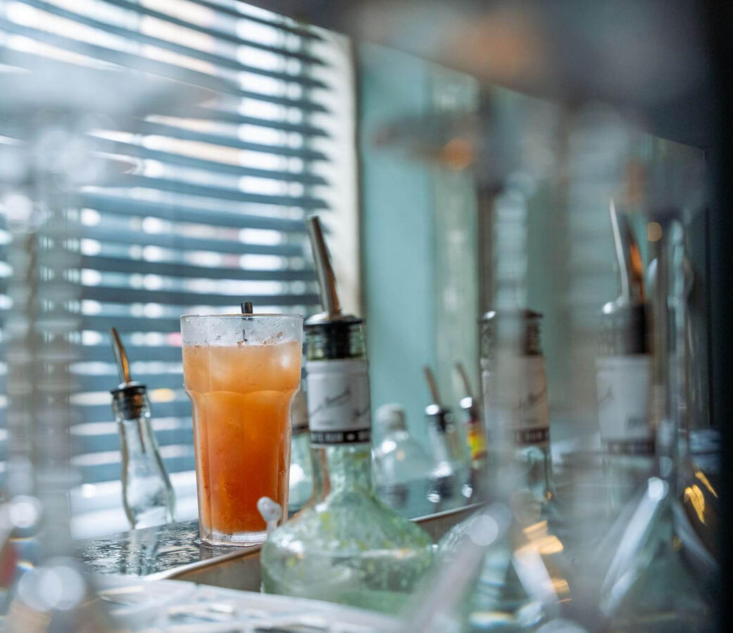Vers bereide cocktail op de professionele mobiele bar met diverse flessen op de achtergrond. Kwaliteit en variatie voor jouw evenement in Rotterdam en Zuid-Holland.