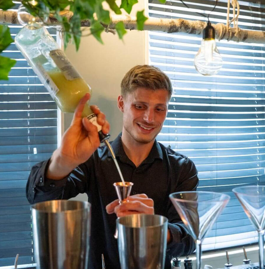 Bartender van De Cocktail Shaker maakt een verse cocktail tijdens een interactieve workshop op locatie in Rotterdam.