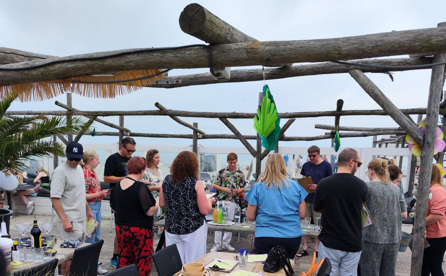 Deelnemers leren cocktails shaken tijdens een interactieve workshop van De Cocktail Shaker op het strand van Hoek van Holland.